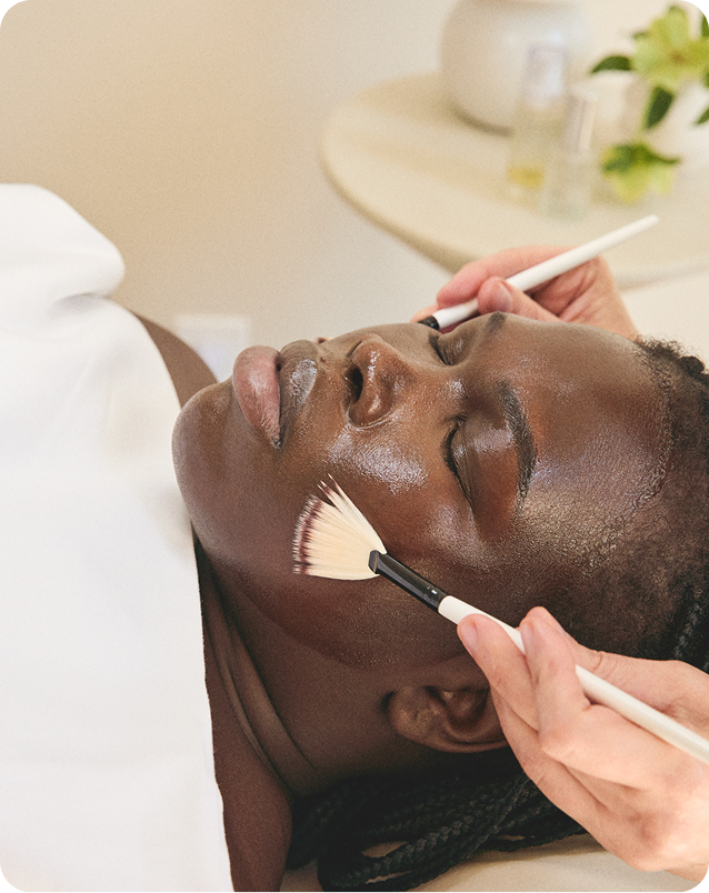 Esthetician performing facial treatment with brushes