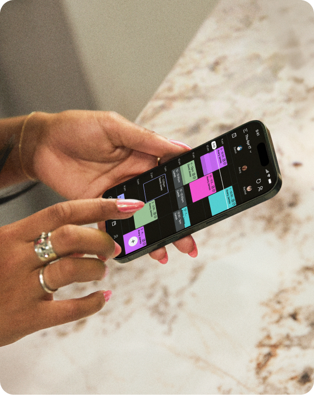 Hands holding phone with GlossGenius calendar app